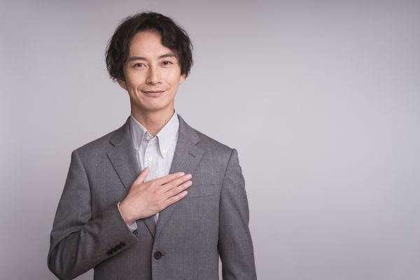 胸を抑えるスーツの男性